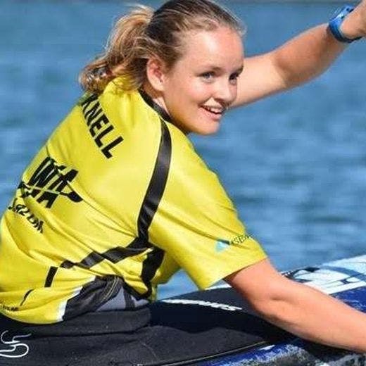 Person wearing a yellow shirt rowing a blue canoe and smiling