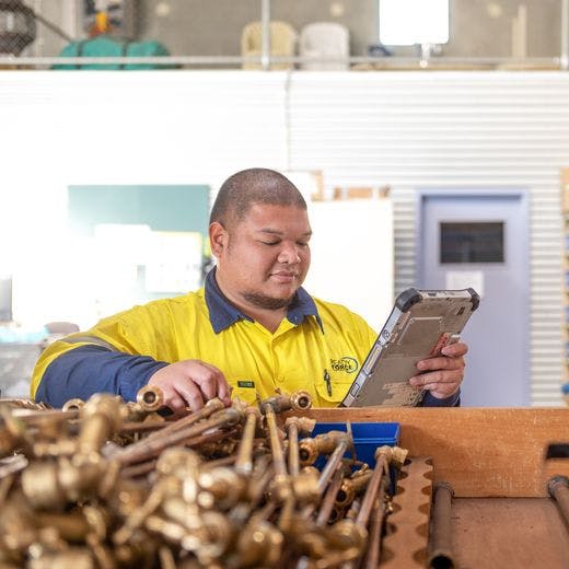 Person looking at tablet in front of tray of pipes and fittings.