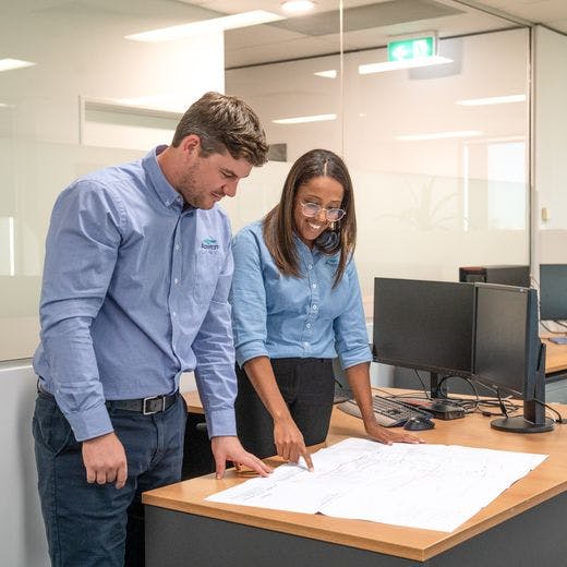Two people standing at a table and looking down at plans.