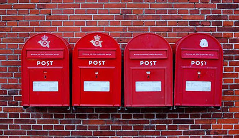 4 post boxes in a row, hanging from a brick wall