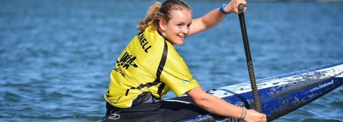 Person wearing a yellow shirt rowing a blue canoe and smiling