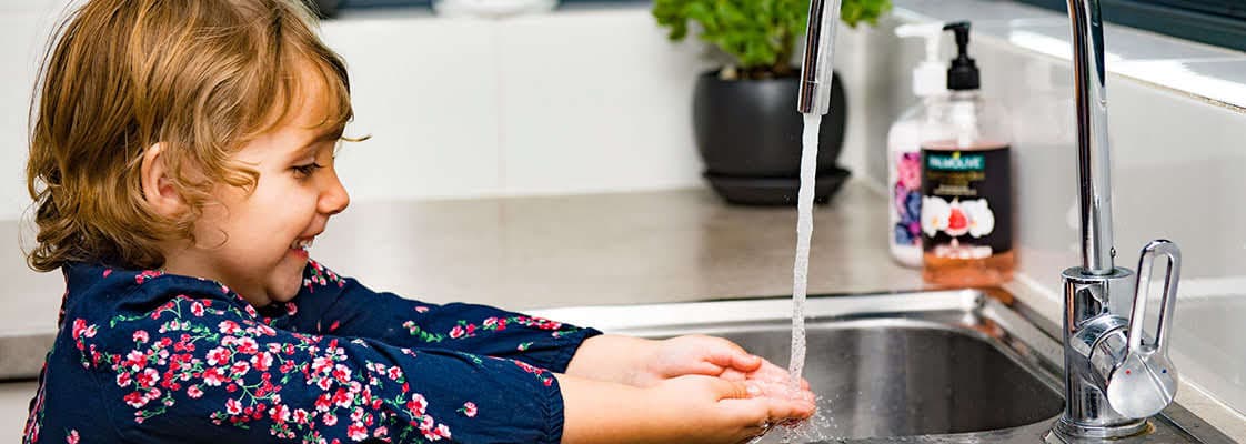 Child washing hands at a sink.