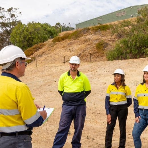 Group of people in hi-vis standing on sand dune.