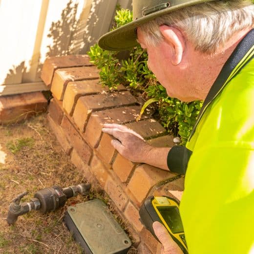 Aqwest employee holding a monitoring device looking over a water meter