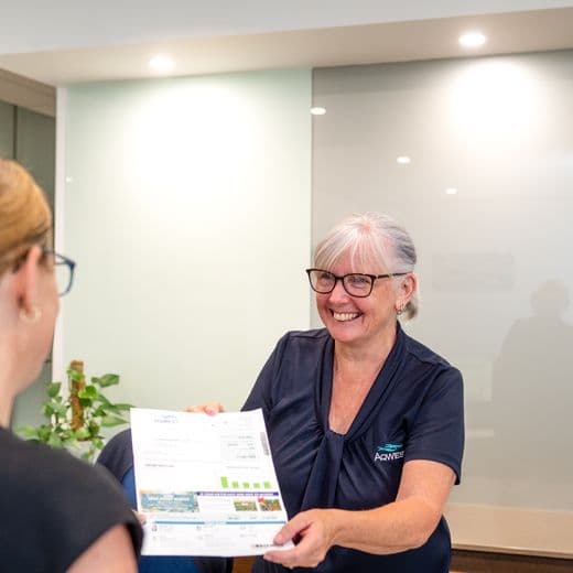 Front desk person handing piece of paper to visitor.