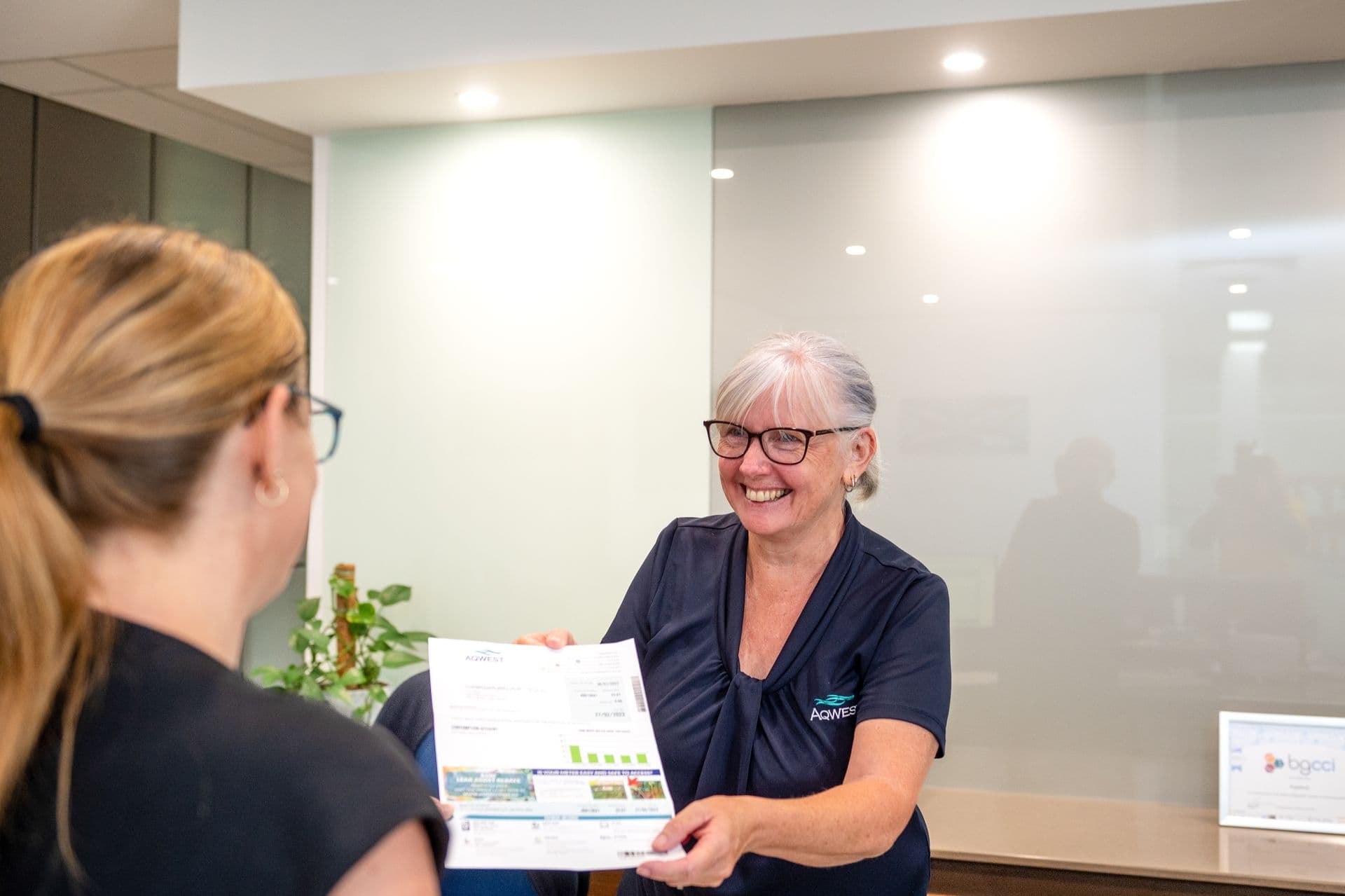 Front desk person handing piece of paper to visitor.