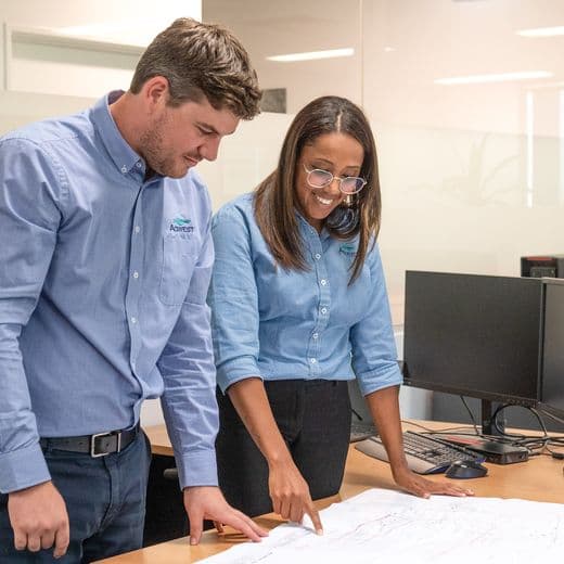 Two people standing at a table and looking down at plans.