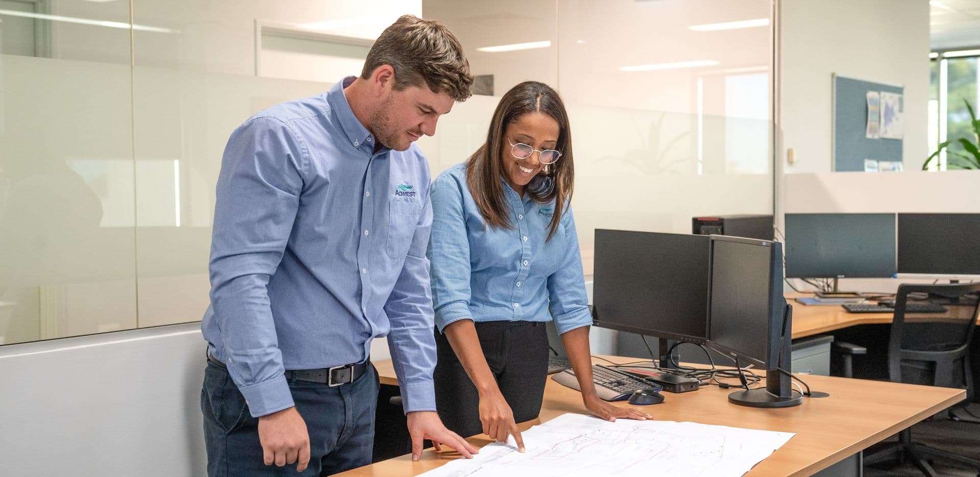 Two people standing at a table and looking down at plans.