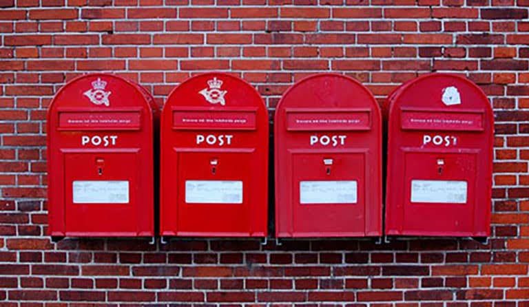 4 post boxes in a row, hanging from a brick wall